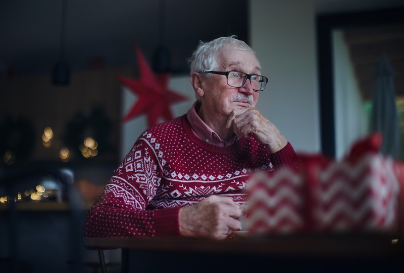 Elderly man with dementia sits in his home waiting for family to come during the holidays.