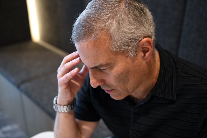 Man holding his forehead, managing stress and taking a moment to breathe.