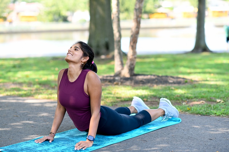 Young woman stretching in the park doing stretches for back pain. 