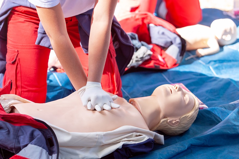 Woman performs chest compressions on a doll to teach CPR