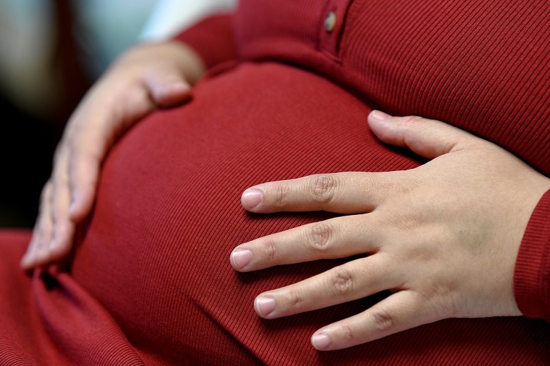 woman's hands holding her pregnant belly, feeling contractions, braxton hicks or labor