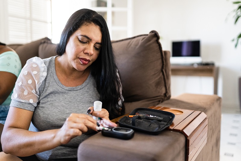 Woman checking blood sugar level at home, signs of diabetes in women