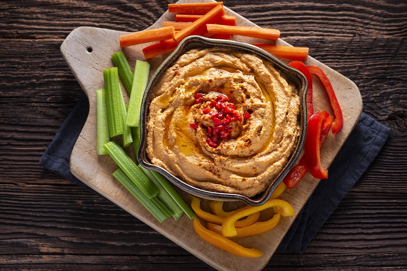 Roasted red pepper hummus with cut peppers around out.