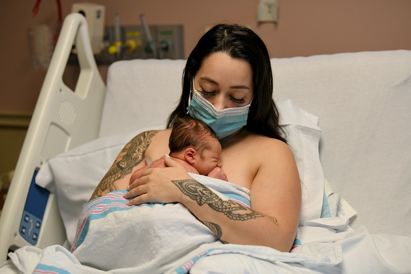 Mother holding her newborn baby on her chest. 