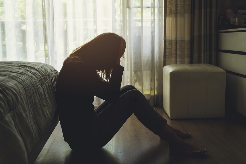 Woman sitting on the floor upset and emotional after a miscarriage 