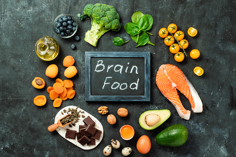 Brain food concept with various food like avocado, salmon and nuts on a chalkboard.