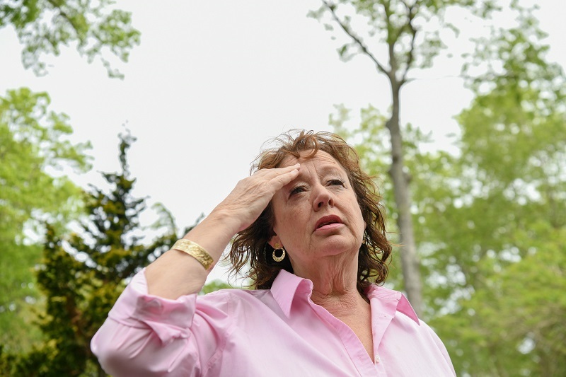 Woman standing outside, experiencing vertigo and dizziness.