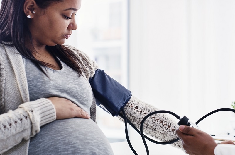 A pregnant young woman getting her blood pressure checked by a doctor at a clinic