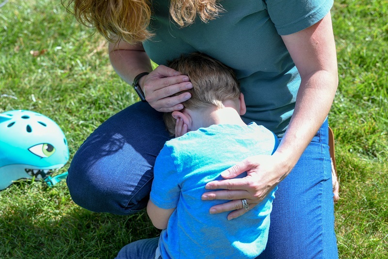 Mother comforting her toddler son with a hug.