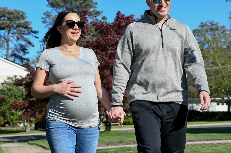 Pregnant woman walking with her husband outside to get exercise.