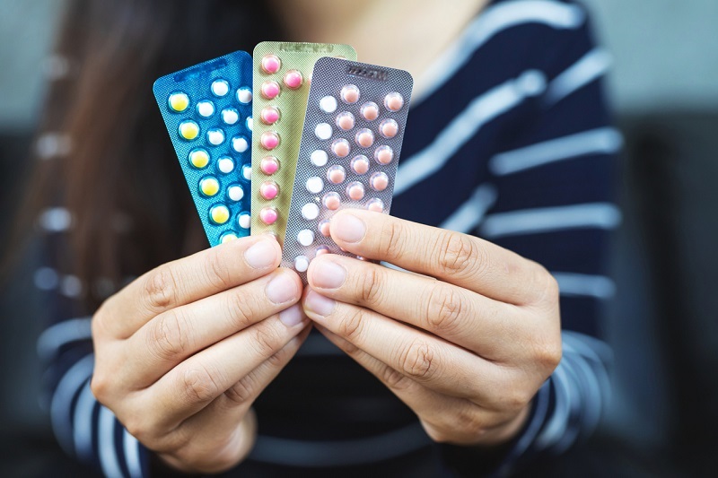 Woman's hands holding birth control pill options.