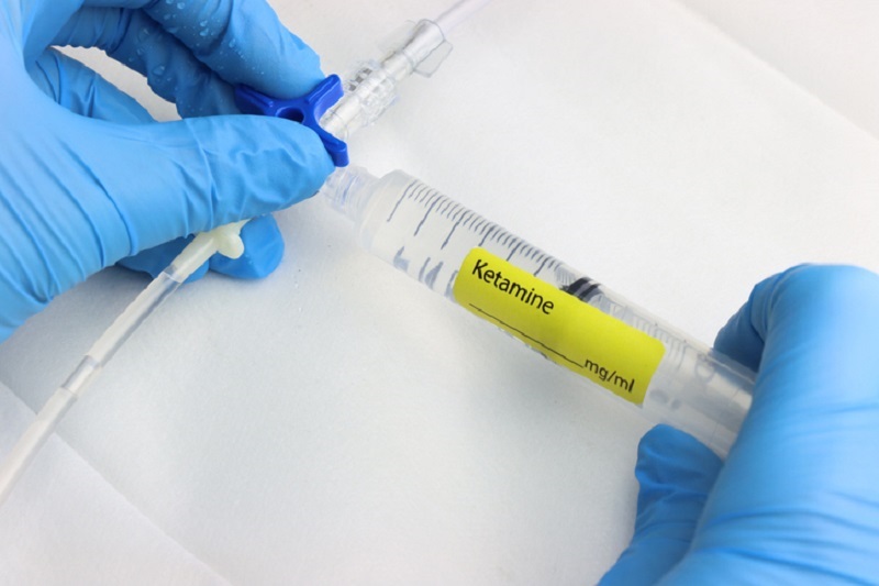 Professional wearing gloves injecting ketamine to be taken intravenously.