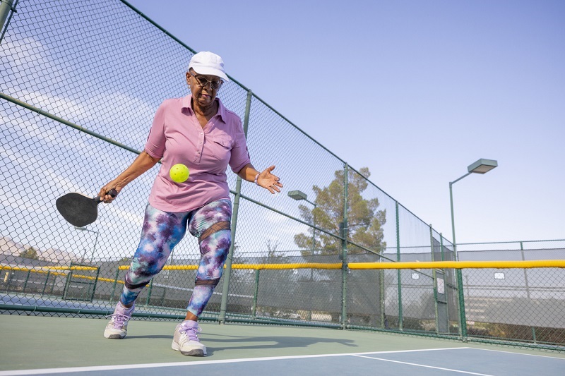 Older woman about to hit a ball in a pickleball match.