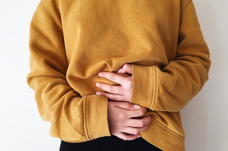 Close up of a woman holding her stomach, feeling a hernia.