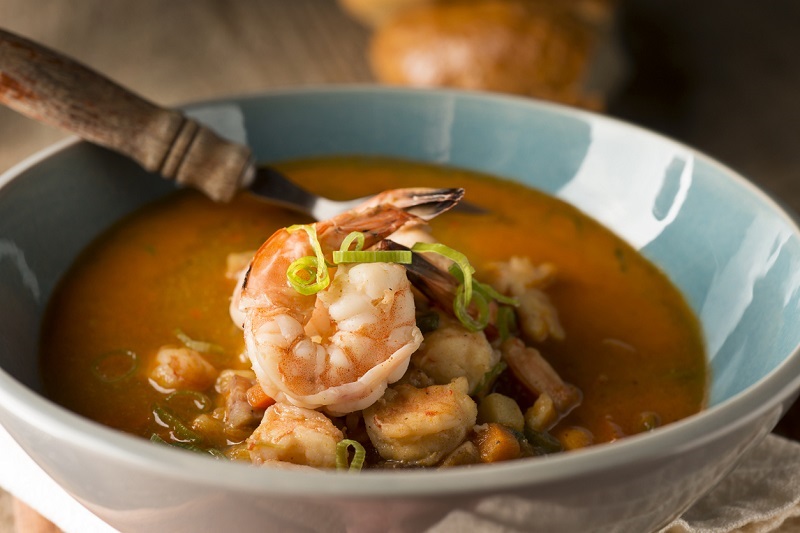 Shrimp and white bean stew in a bowl with a spoon.