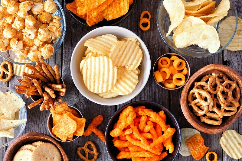 An assortment of chips and processed snacks in bowls on a table