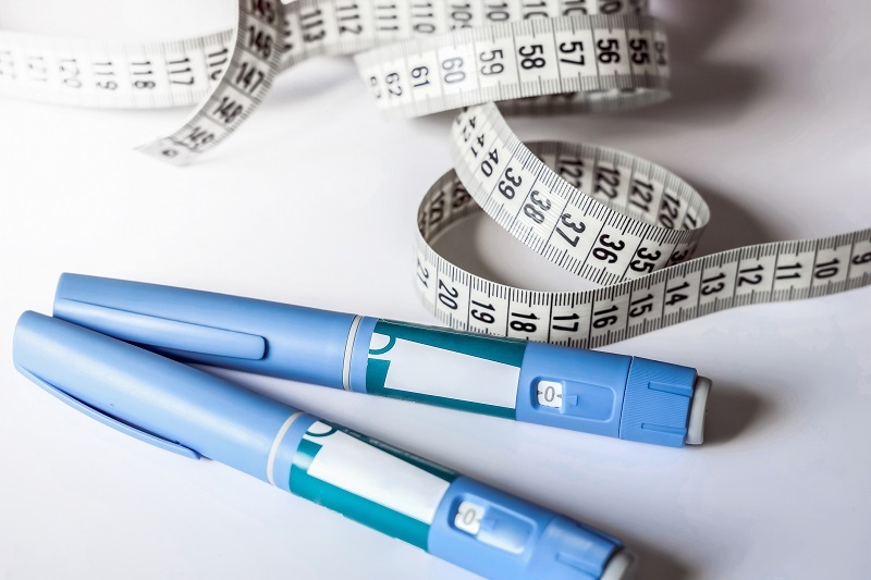 Ozempic or weight loss injection pens with some tape measures laid around them.