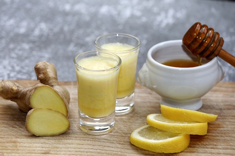 Drink with ginger root, honey and lemon on a wooden background.
