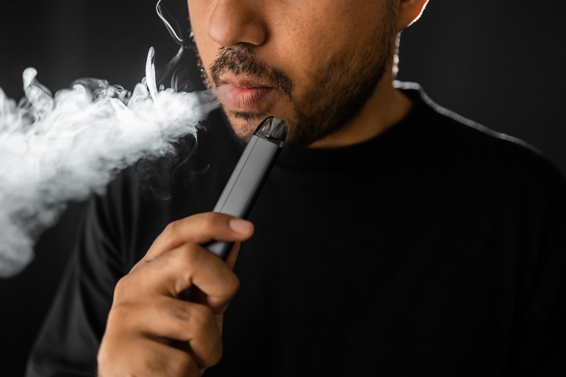 Close-up mouth of a man smoking an electronic cigarette.