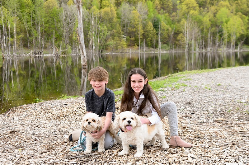 Children, Aiden and Lia, hanging out with their dogs in the park by a pond