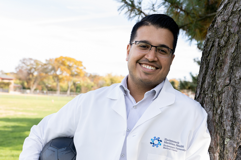 A group of senior adults standing behind chairs doing balance exercises.