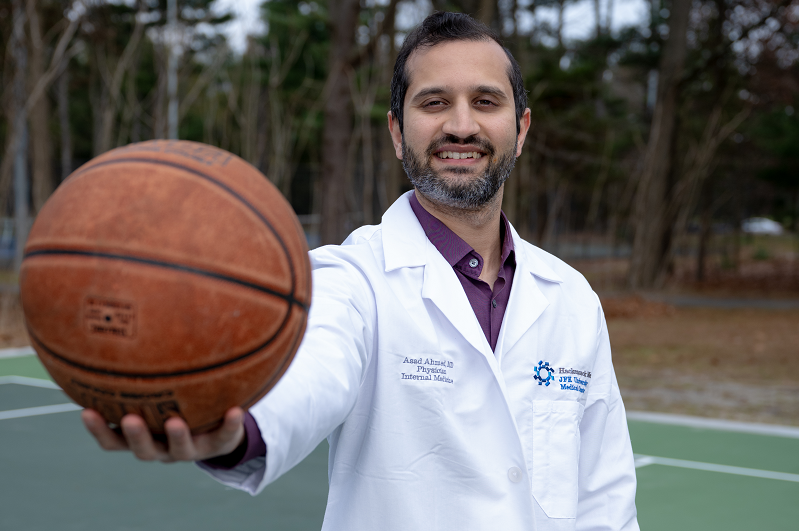 Primary care doctor, Dr. Asad Ahmed holding a basketball and smiling.