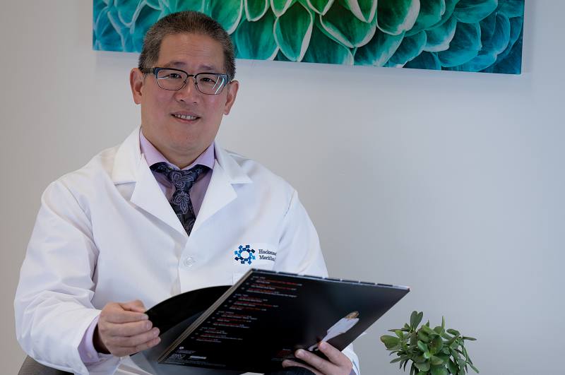 Michael Kuo, M.D., sitting in a chair, smiling, holding a vinyl record.