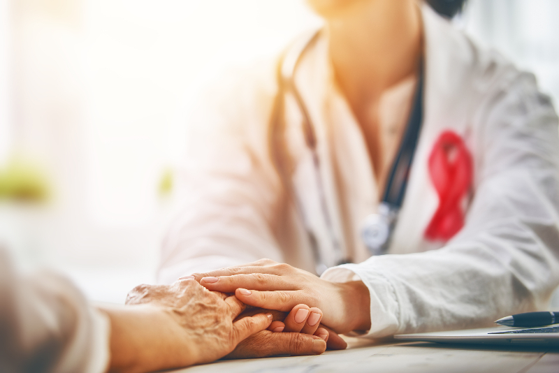 Pink ribbon for breast cancer awareness. Female patient listening to doctor in medical office. Support people living with tumor illness.
