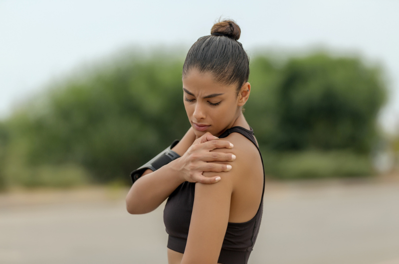 Woman clutches her shoulder after a workout.