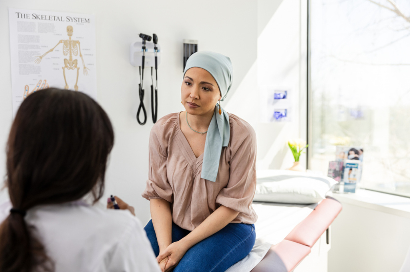 An adult female cancer patient listens as a doctor talks to her about potential clinical trials.