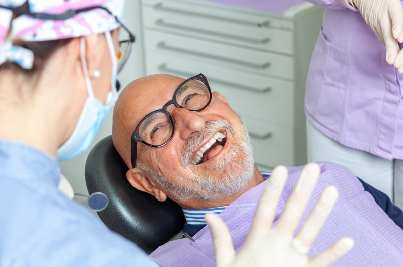Happy senior man smiling at a female dentist during a dental checkup at the clinic.