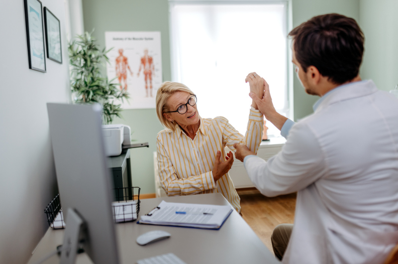 Mature woman having her arm checked by doctor at doctor's office