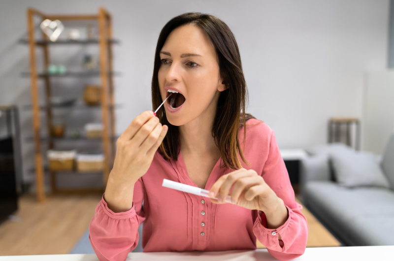 Brunette woman taking an at-home hormone test with a saliva mouth swab.