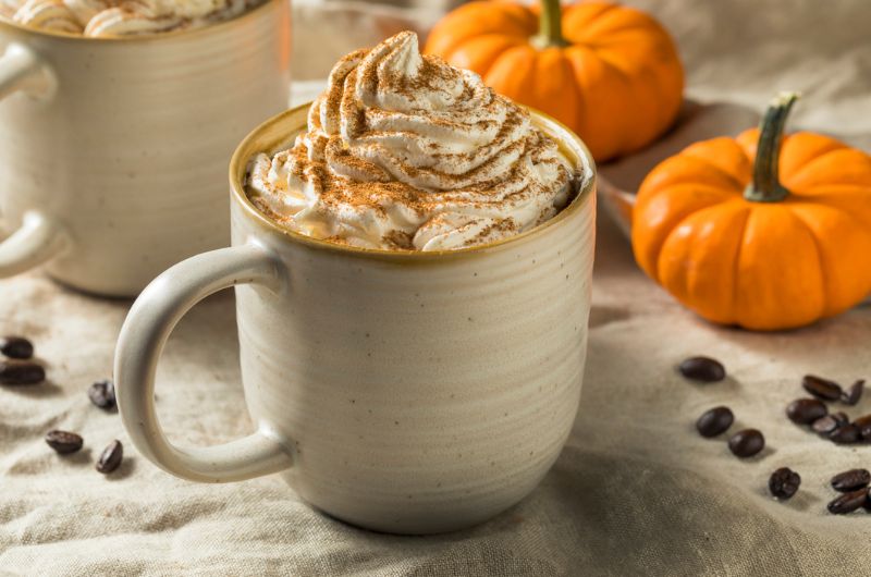 A coffee mug filled with a pumpkin spiced latte sits on a table. 