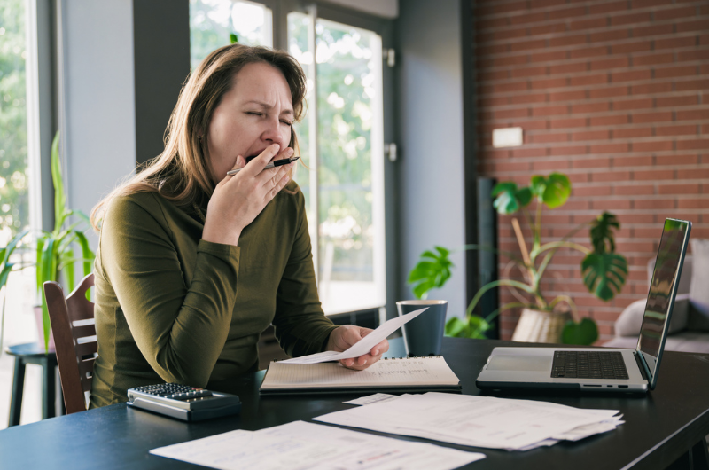 A tired, middle-aged business woman yawns at her workplace.
