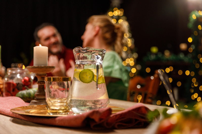Avoid drinking alcohol by opting for refreshing water with lemon and cucumber slices, as shown served on a dining table during a dinner party.
