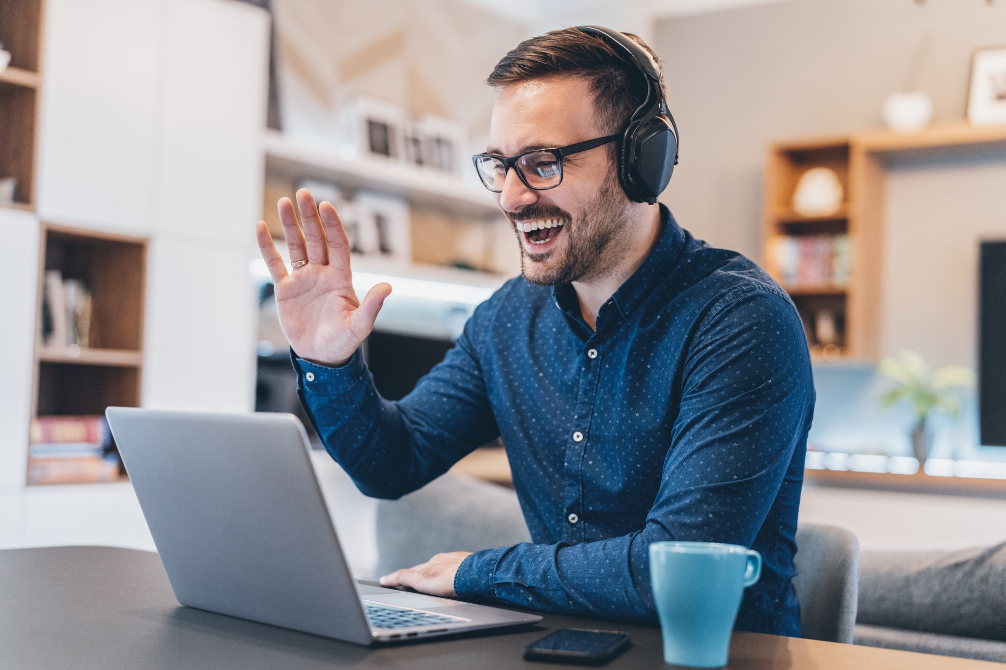 guy waving on a video call wearing headphones