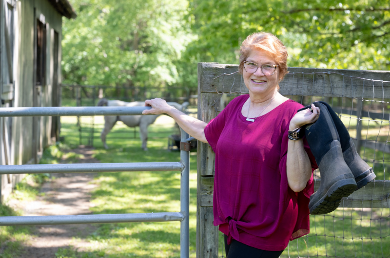 Urogynecology patient Wendy Young stands in front of a horse pen on her farm in New Jersey.