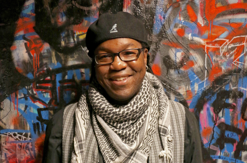Jakubu Griffin of Teaneck, New Jersey, stands in front of a colorful wall and smiles.
