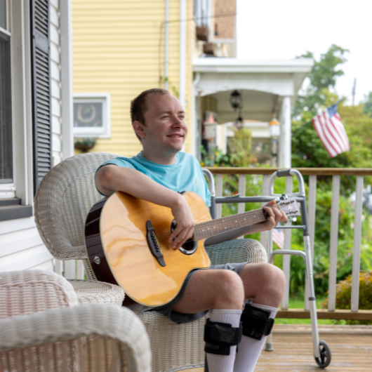 Jack looks off into the distance as he strums his guitar.
