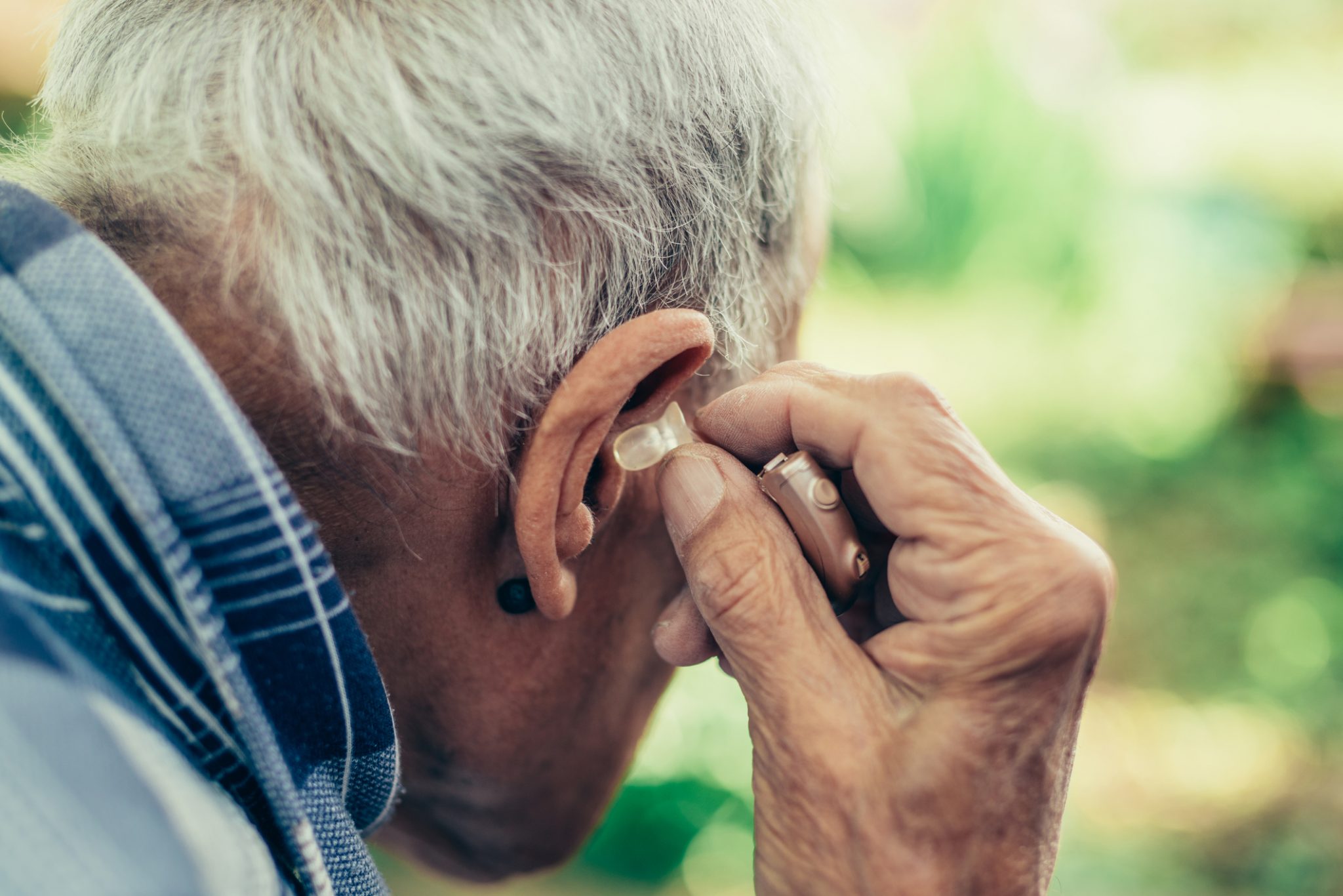 Man placing hearing aid in ear