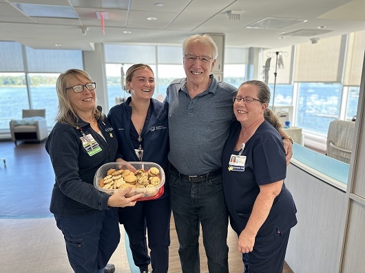 Albert standing with nurses in the infusion center, smiling and hugging each other. 