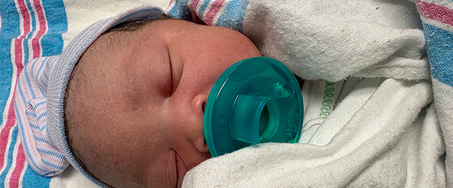 New born baby with pacifier laying down