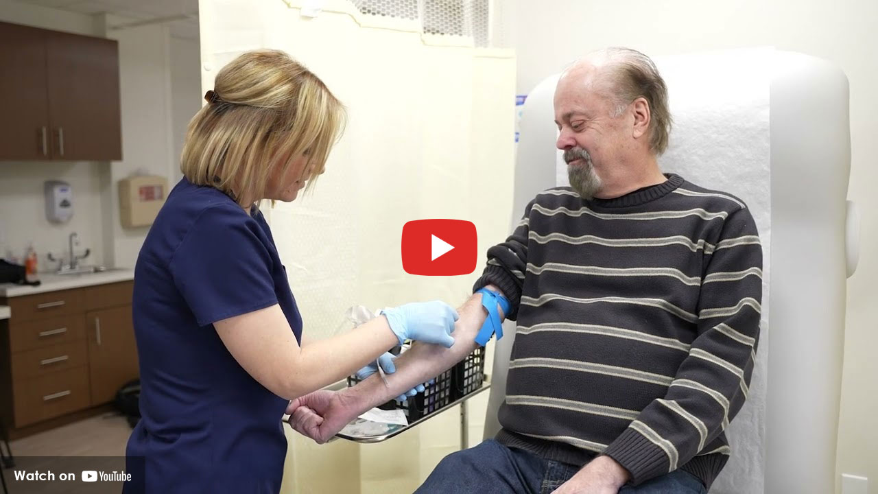 nurse getting ready to draw blood from a man sitting in a chair