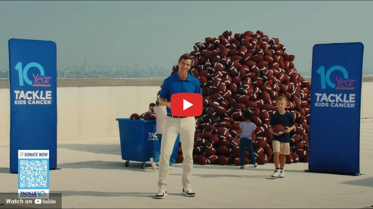 Eli Manning standing on rooftop celebrating Tackle Kids Cancer
