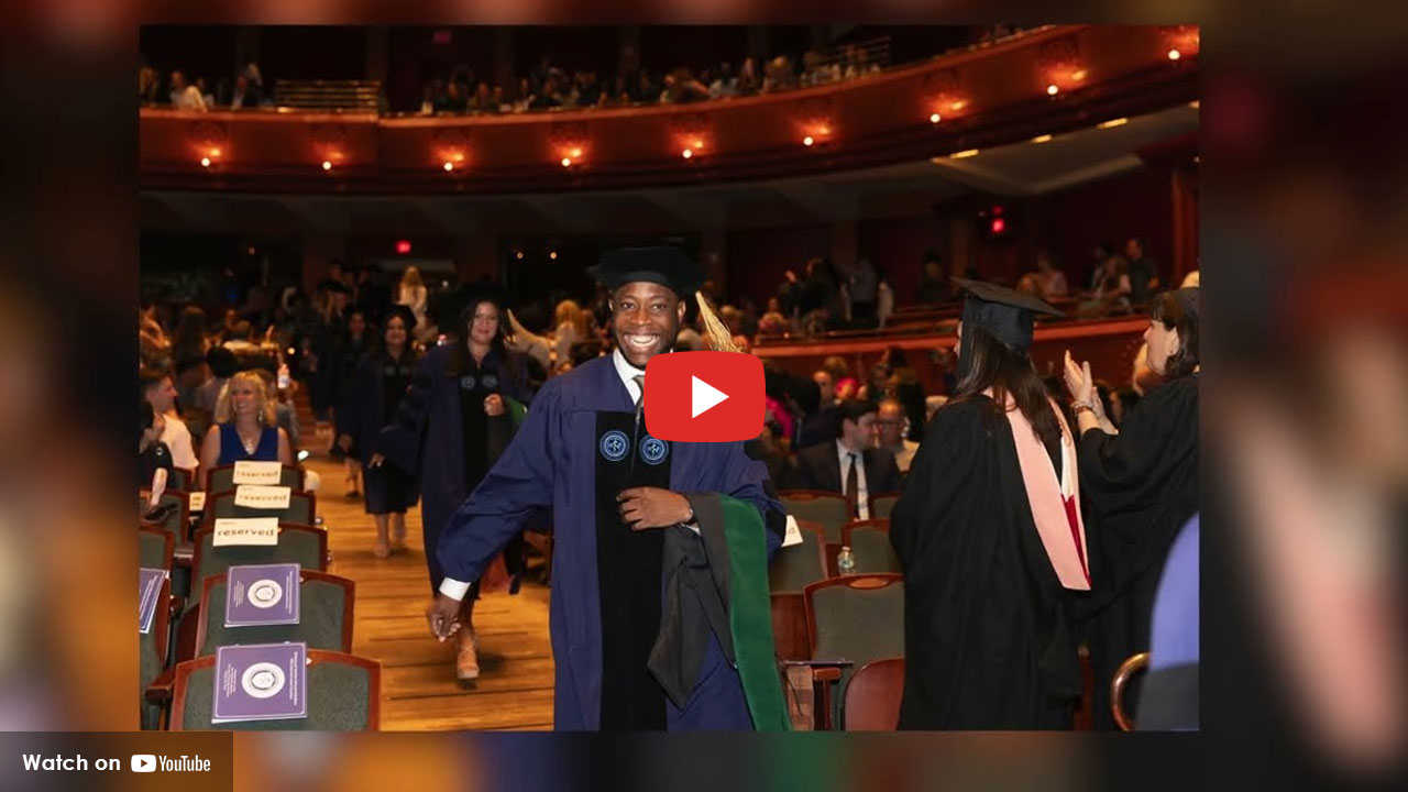 Graduate in cap and gown walking through an auditorium during a commencement ceremony