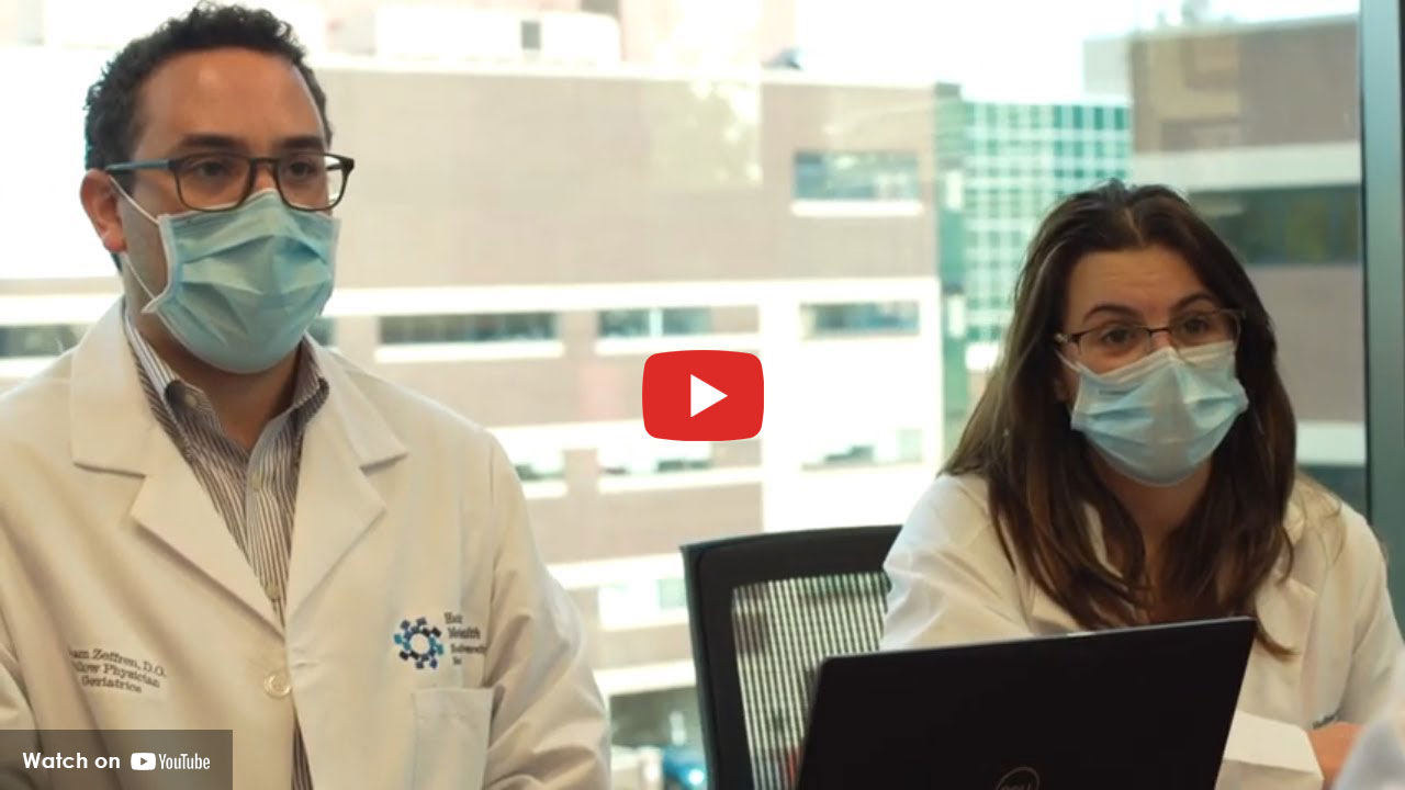 Two doctors wearing masks seated at a table during a meeting