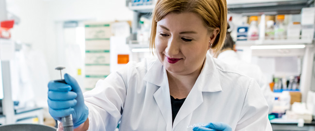 Female scientist in a lab coat using a pipette in a laboratory