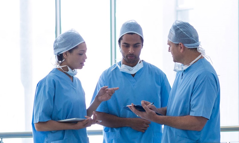 Team of surgeons in blue scrubs discussing patient care in a hospital.